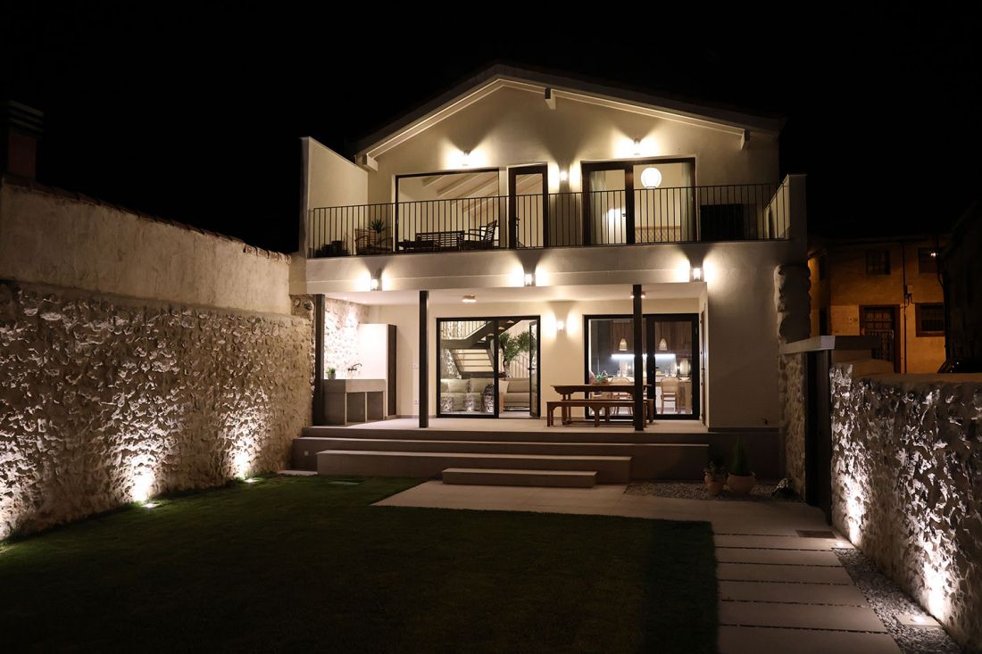Vista nocturna de la piscina y exterior de la casa