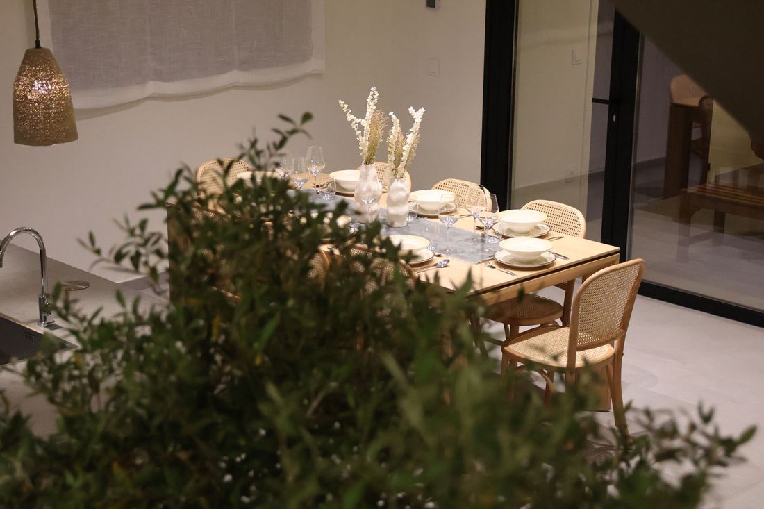 Vista de la mesa comedor de madera con planta de olivo en primer plano