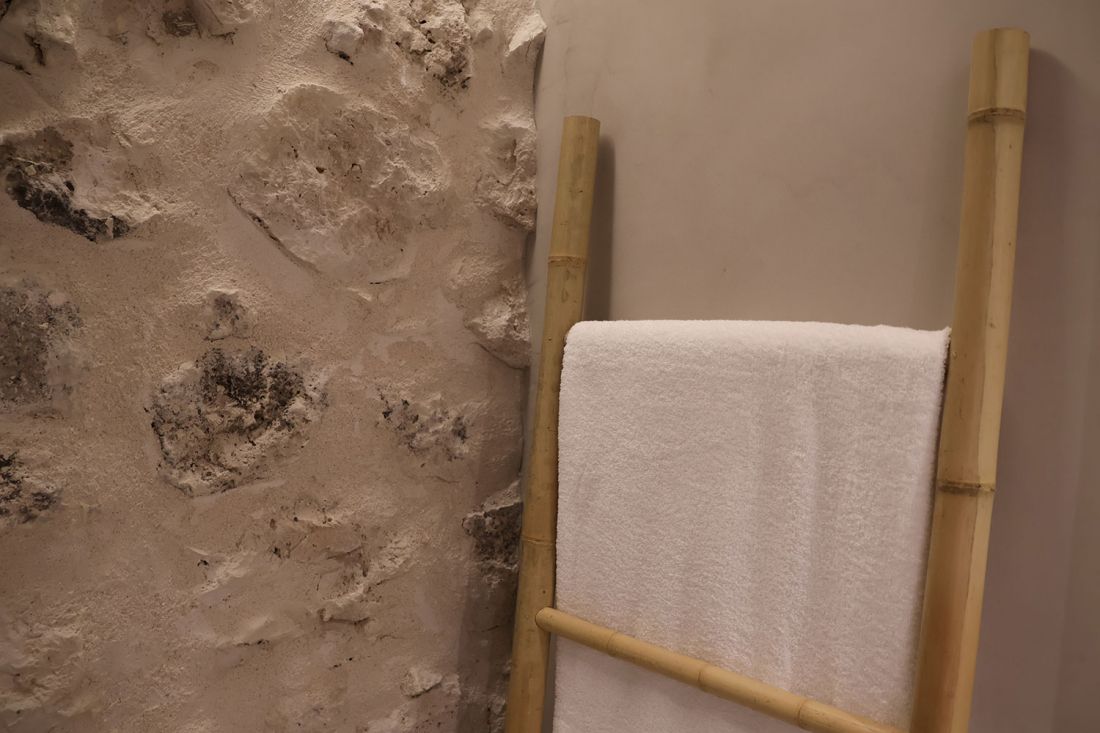Toallero en interior de dormitorio con pared de piedra