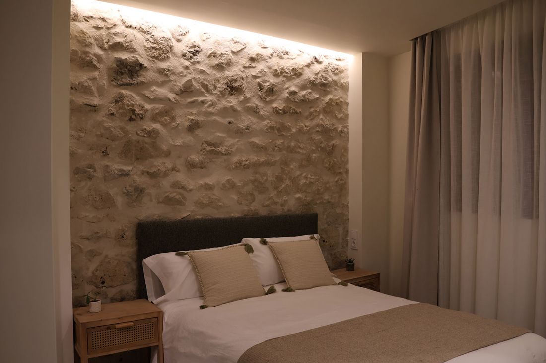 Interior gde dormitorio con cama de matrimonio y pared de piedra