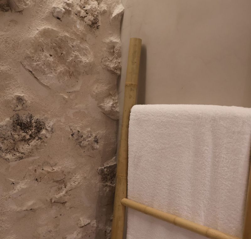 Toallero en interior de dormitorio con pared de piedra
