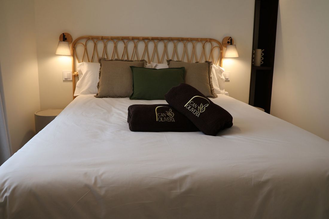 Cama de matrimonio con cabecera de madera en dormitorio en tonos ocres