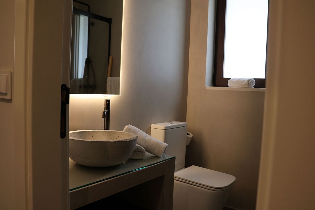 Vista de baño minimalista con lavabo de piedra en tonos grises y ocres