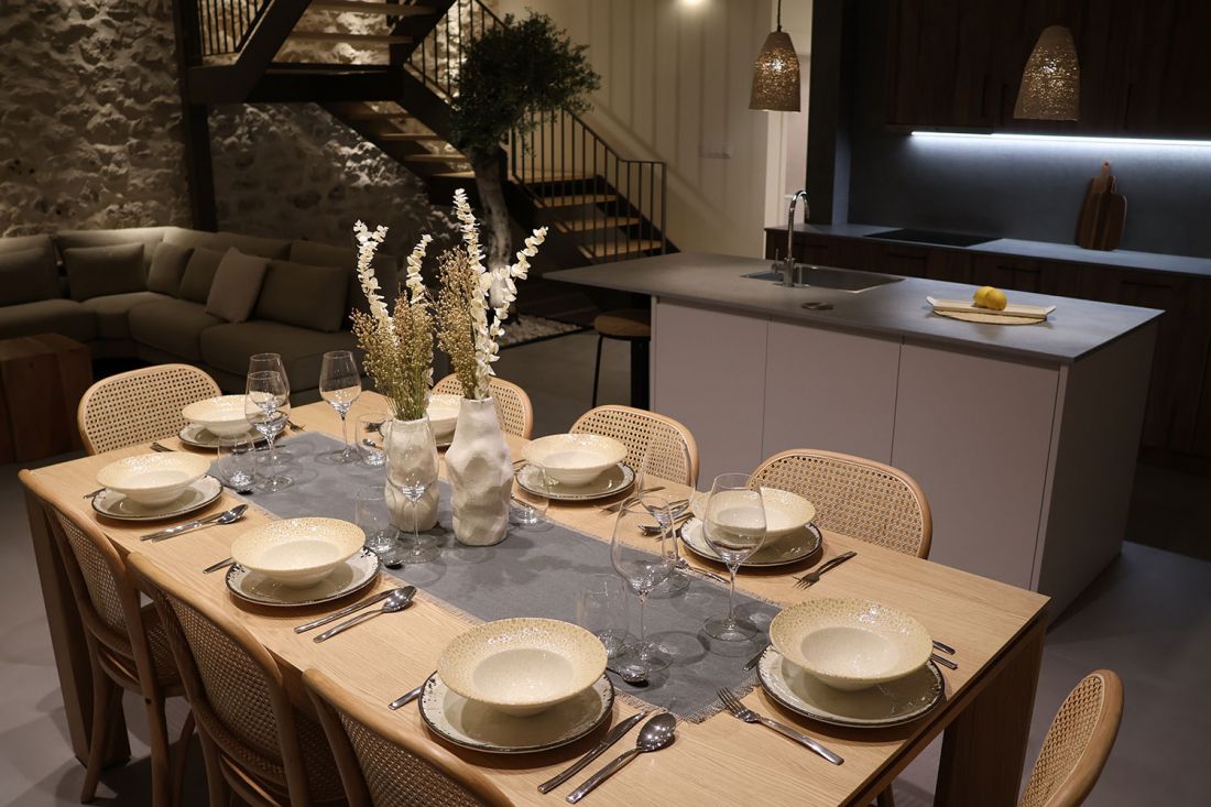 Amplia mesa de comedor de madera preparada con vajilla, cubertería y cristalería