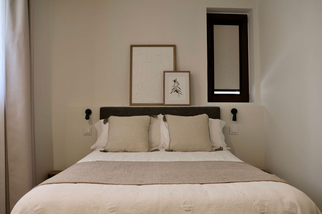 Dormitorio de matrimonio minimalista con cama con colcha blanca